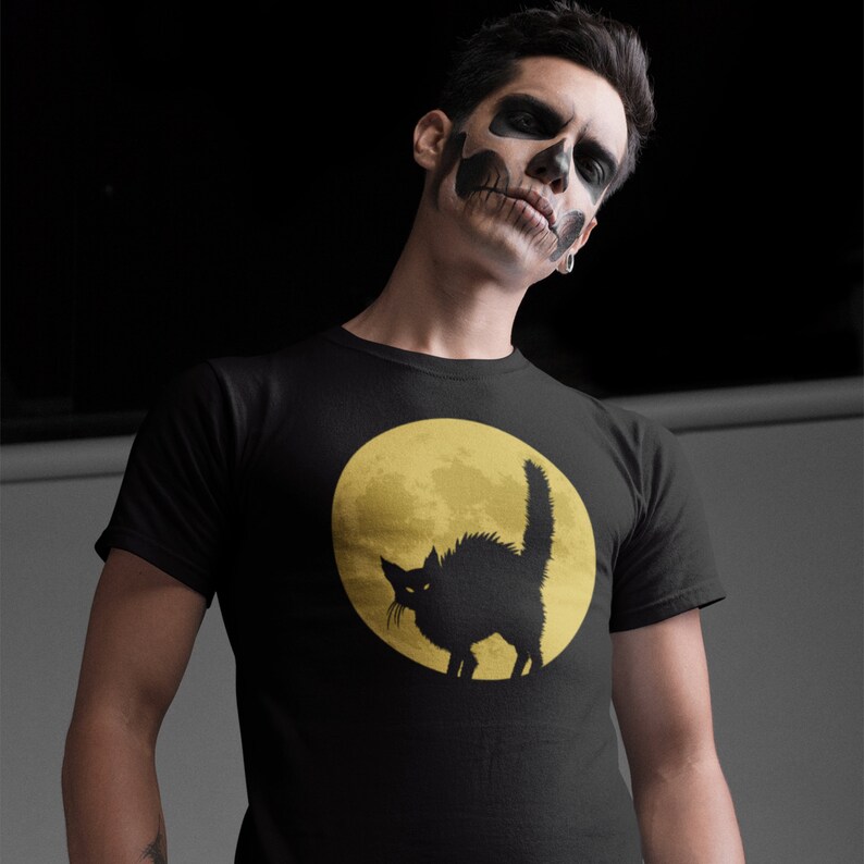 May include: A black t-shirt with a graphic of a black cat silhouetted against a yellow moon.