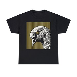 May include: Black t-shirt featuring a graphic print of a white dove's head with a yellow eye, set against a background of vertical olive green stripes.