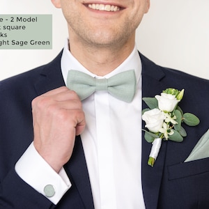 The front-view model with dark blue suit wears the Light sage green color linen pretied bow tie 2 Model, pocket square, and cufflinks.