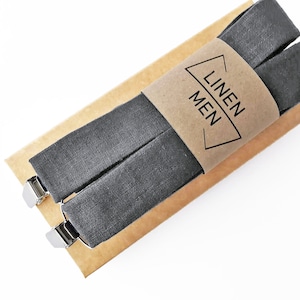 May include: Gray linen suspenders with silver clips, packaged on a brown paper card with the text "LINEN MEN" printed on it.