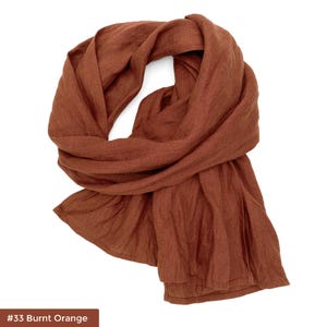 May include: A burnt orange linen scarf. The scarf is folded and draped over a white background. #33 Burnt Orange
