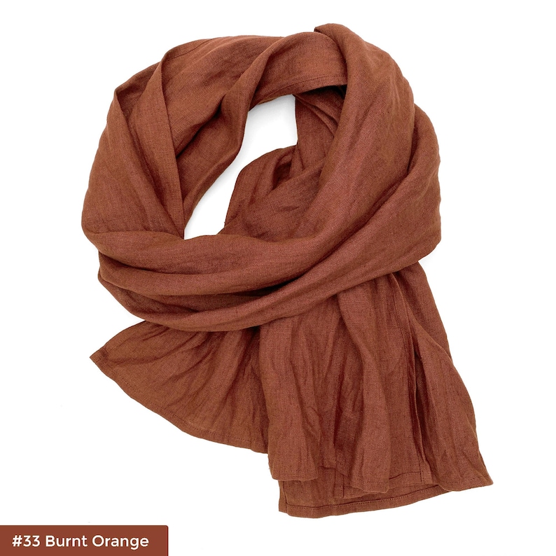 May include: A burnt orange linen scarf. The scarf is folded and draped over a white background. #33 Burnt Orange