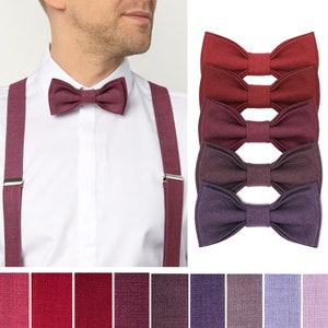 May include: Five bow ties in different shades of burgundy and purple. The bow ties are made of a textured fabric and are arranged in a row from darkest to lightest.