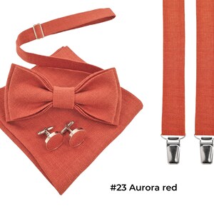 Linen aurora red color pre-tied bow tie shown with the same color cufflinks and aurora red folded pocket square and aurora red suspenders with metal clips. The bow tie has an attached adjustable strap.