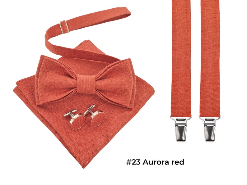Linen aurora red color pre-tied bow tie shown with the same color cufflinks and aurora red folded pocket square and aurora red suspenders with metal clips. The bow tie has an attached adjustable strap.