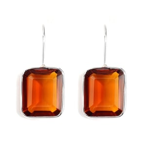 May include: A pair of silver dangle earrings with large, rectangular, amber-colored gemstones.