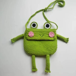May include: Green crocheted frog-shaped shoulder bag with pink cheeks, white eyes, and a black mouth.