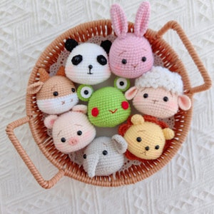 May include: A wicker basket filled with crocheted animal plushies. The plushies include a panda, a frog, a pig, a bunny, a sheep, a lion, and an elephant. Each plush has a cute, cartoon-like face.