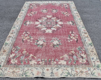 May include: A rectangular area rug featuring a deep red central field with a central geometric medallion and floral motifs in shades of cream, green, and blue. The rug is framed by a wide cream-colored border with intricate floral and geometric patterns.