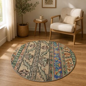 May include: A round area rug featuring a multi-colored pattern with vertical stripes of floral and geometric motifs in shades of blue, orange, green, and cream. The rug has a low-pile texture and a finished grey edge, lying flat on a wooden floor.