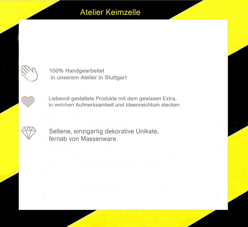 May include: A white square sign with a yellow and black diagonal striped border. The text reads Atelier Keimzelle, followed by three lines of German text accompanied by icons of a hand, a heart, and a diamond, detailing production.