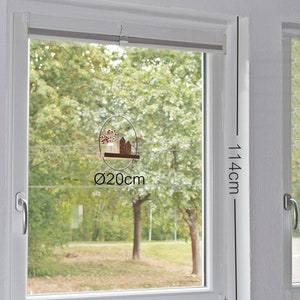 May include: A hanging window decoration featuring a circular metal frame with a diameter of 20 cm, holding a small wooden house and a glass vase with red berries. The window frame is labeled with dimensions of 114 cm by 96 cm.