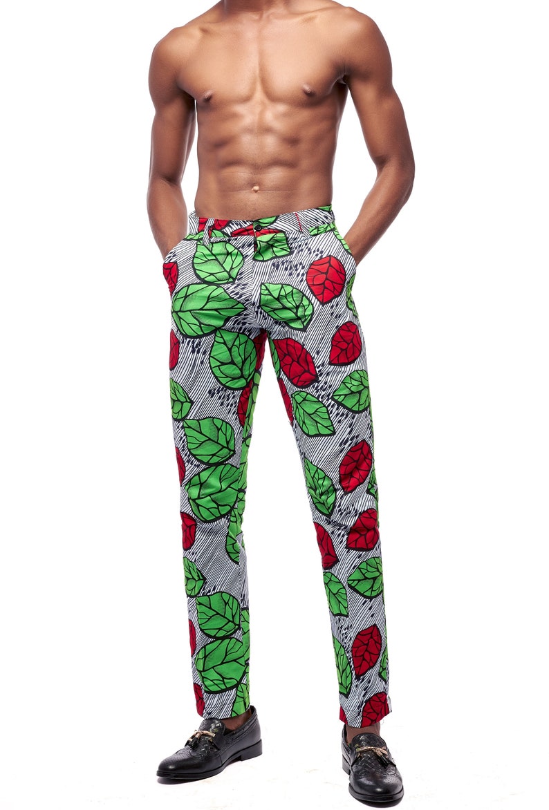 Puede incluir: Pantalones ajustados con un llamativo dise&ntilde;o de hojas verdes y rojas sobre un fondo a rayas blancas y negras. Los pantalones se combinan con zapatos de cuero negros. Una declaraci&oacute;n de moda audaz.