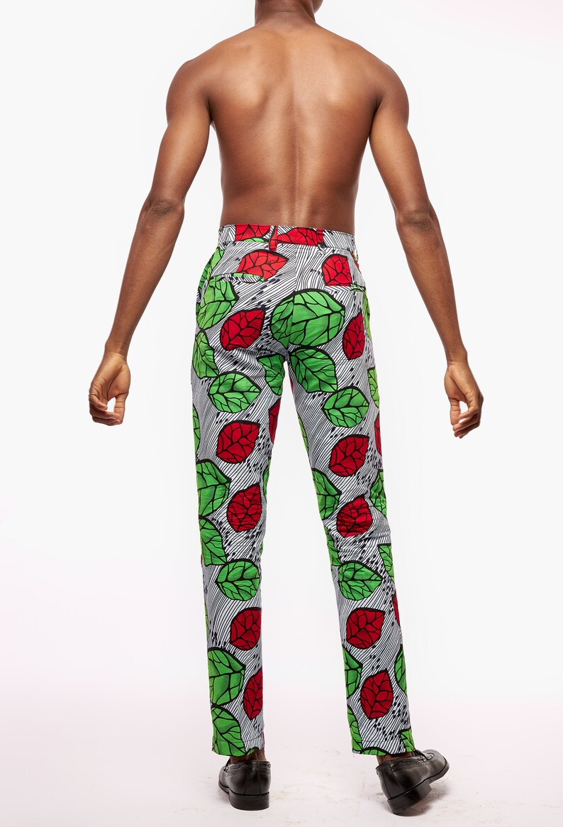 Puede incluir: Pantalones estampados con un patr&oacute;n de hojas rojas y verdes sobre un fondo a rayas blancas y negras. Los pantalones son a medida y parecen estar hechos de una tela ligera. Los pantalones se llevan con zapatos de vestir negros.