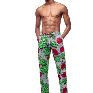 Puede incluir: Pantalones ajustados con un llamativo estampado de hojas verdes y rojas sobre un fondo a rayas grises y blancas. Los pantalones tienen un cintur&oacute;n a juego y se combinan con zapatos de cuero negro. El estilo es audaz y llamativo.