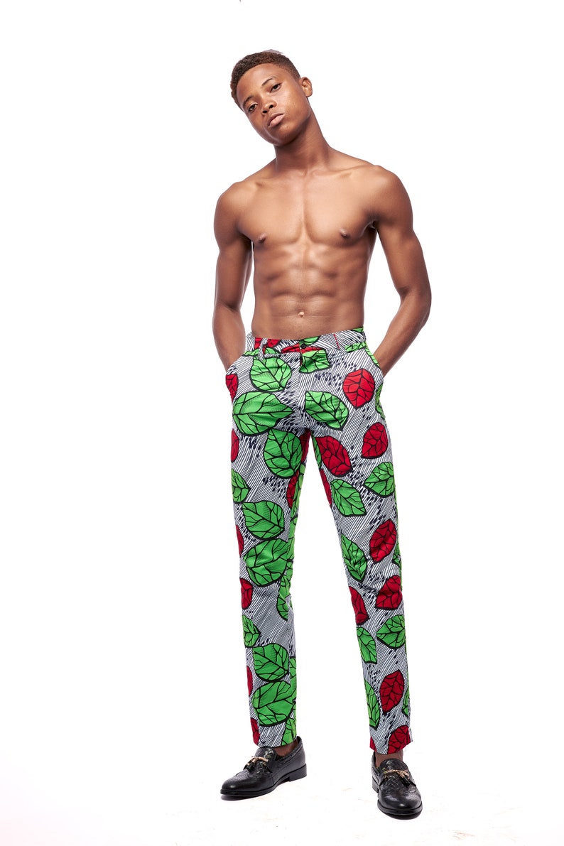 Puede incluir: Pantalones ajustados con un llamativo estampado de hojas verdes y rojas sobre un fondo a rayas grises y blancas. Los pantalones tienen un cintur&oacute;n a juego y se combinan con zapatos de cuero negro. El estilo es audaz y llamativo.