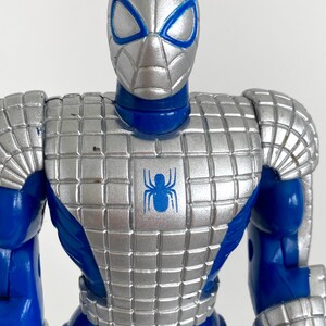 K&ouml;nnte beinhalten: Eine blaue und silberne Actionfigur von Spider-Man, die eine silberne R&uuml;stung mit einem Spinnenlogo auf der Brust tr&auml;gt.