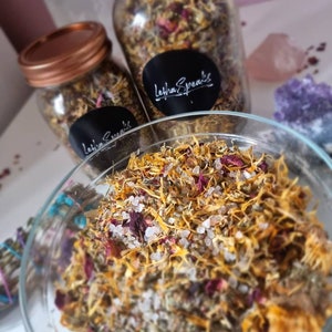 Pode incluir: Um frasco de vidro cheio de uma mistura de ervas secas, flores e sal. O frasco tem uma tampa de cobre e um rótulo preto com o texto "Letha Speaks".