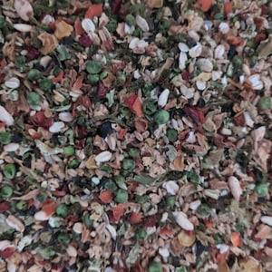 May include: Close-up of a mix of dried vegetables and grains. The blend includes green peas, orange carrots, and white grains, with a variety of other colorful ingredients. The texture is coarse and varied, suggesting a healthy food mix.