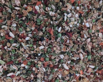 May include: Close-up of a mix of dried vegetables and grains. The blend includes green peas, orange carrots, and white grains, with a variety of other colorful ingredients. The texture is coarse and varied, suggesting a healthy food mix.