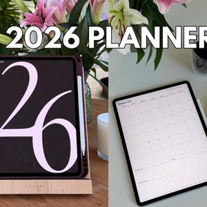 May include: A digital 2026 planner displayed on a tablet. The tablet is in a wooden stand, with the number "26" prominently displayed. A second tablet shows a calendar view. The image includes a stylus, flowers, and a cup of coffee.