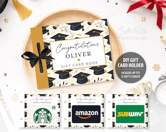 May include: A graduation-themed gift card book with the text "Congratulations Oliver GIFT CARD BOOK". The cover is decorated with graduation caps and a black bow. Includes gift cards for Starbucks, Amazon, and Subway.