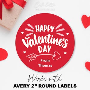 May include: A red round label with the text "HAPPY Valentine's DAY" and "From Thomas" in white. The label is surrounded by red heart shapes and a gift box with a red ribbon. The text "Works with AVERY 2" ROUND LABELS" is also present.