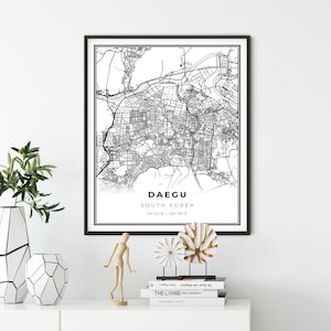 May include: Black and white city map print of Daegu, South Korea with the city's name and coordinates, 35°52'N | 128°36'E, printed on white paper and framed in a black frame.