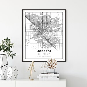 May include: A black and white map print of Modesto, California. The map shows the city streets and landmarks. The text "MODESTO, CALIFORNIA" and the coordinates "37°39′41″N 120°59′40″W" are printed below the map.