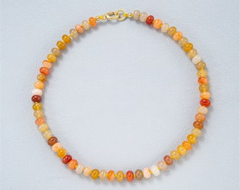 May include: A necklace made of small, round, orange, yellow, and white beads. The necklace is strung on a gold chain.