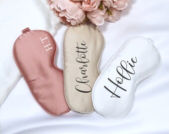 May include: Three satin sleep masks with personalized names. The masks are in pink, beige, and white.