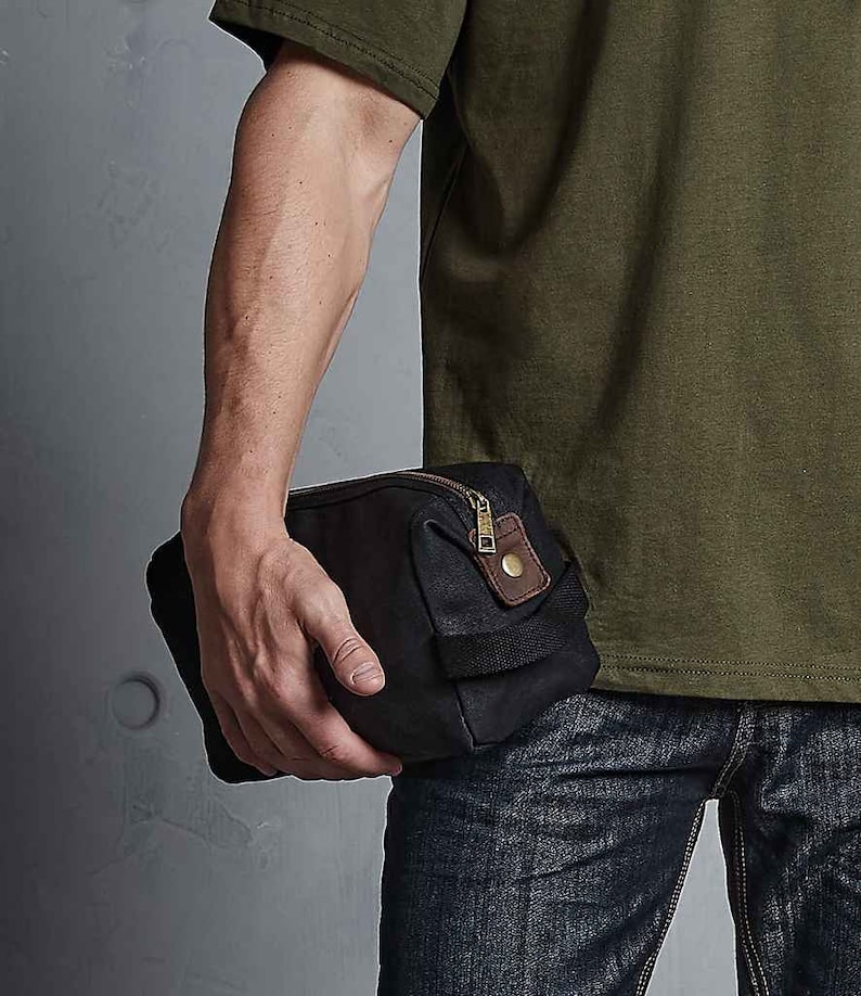 May include: A black canvas wash bag with a brown leather trim and a zip fastening.