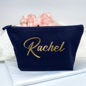 May include: A navy blue zippered pouch with the name "Rachel" written in gold lettering.