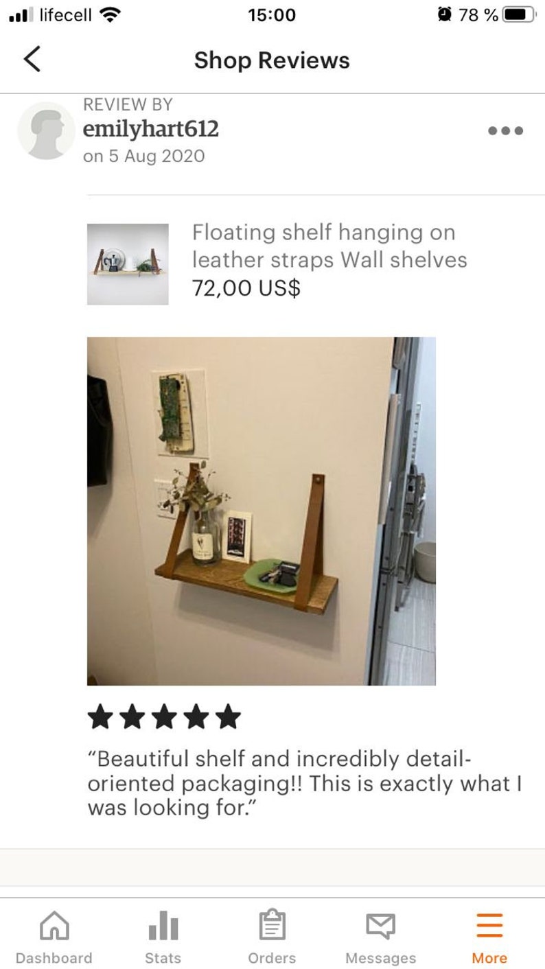 May include: A wooden shelf with leather straps hanging on a white wall. The shelf is 72.00 US$ and is described as "Beautiful shelf and incredibly detail-oriented packaging!! This is exactly what I was looking for."