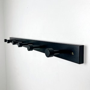 Perchero de pared de madera y metal con rieles negros para entrada.