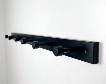 Perchero de pared de madera y metal con rieles negros para entrada.