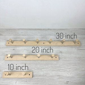May include: Three wooden coat racks with five hooks each. The racks are 10 inches, 20 inches, and 30 inches long.