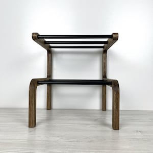 Puede incluir: Un zapatero de madera con dos estantes de metal negro. El zapatero est&aacute; hecho de madera marr&oacute;n claro con un acabado natural.