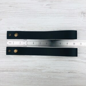 Pu&ograve; includere: Due cinturini in pelle nera con rivetti in ottone e un righello che misura 25,4 cm di lunghezza.