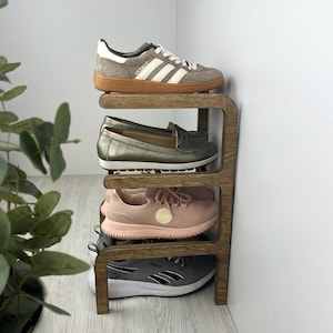 Pu&ograve; includere: Uno scarpiera in legno con quattro ripiani, che contiene quattro paia di scarpe. Le scarpe includono un paio di scarpe da ginnastica bianche, un paio di mocassini marroni, un paio di scarpe da ginnastica rosa e un paio di scarpe da ginnastica grigie.