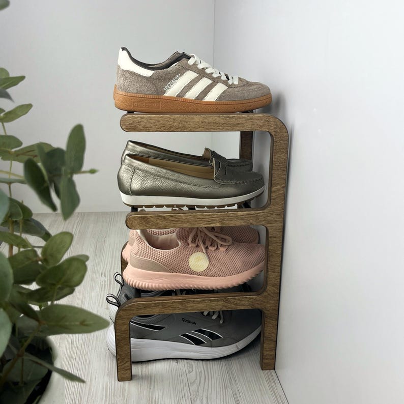 Pu&ograve; includere: Uno scarpiera in legno con quattro ripiani, che contiene quattro paia di scarpe. Le scarpe includono un paio di scarpe da ginnastica bianche, un paio di mocassini marroni, un paio di scarpe da ginnastica rosa e un paio di scarpe da ginnastica grigie.