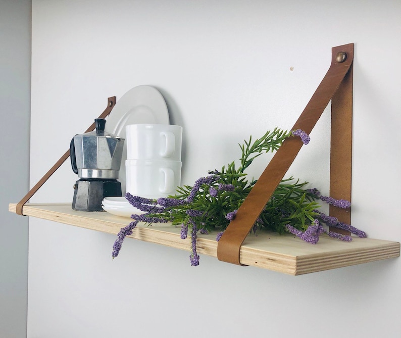 May include: A wooden shelf with leather straps, a coffee pot, cups, and a sprig of lavender.