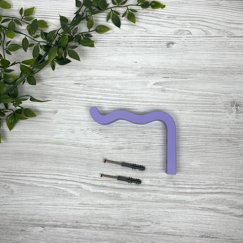 May include: A wavy purple wooden wall hook with two screws for mounting.