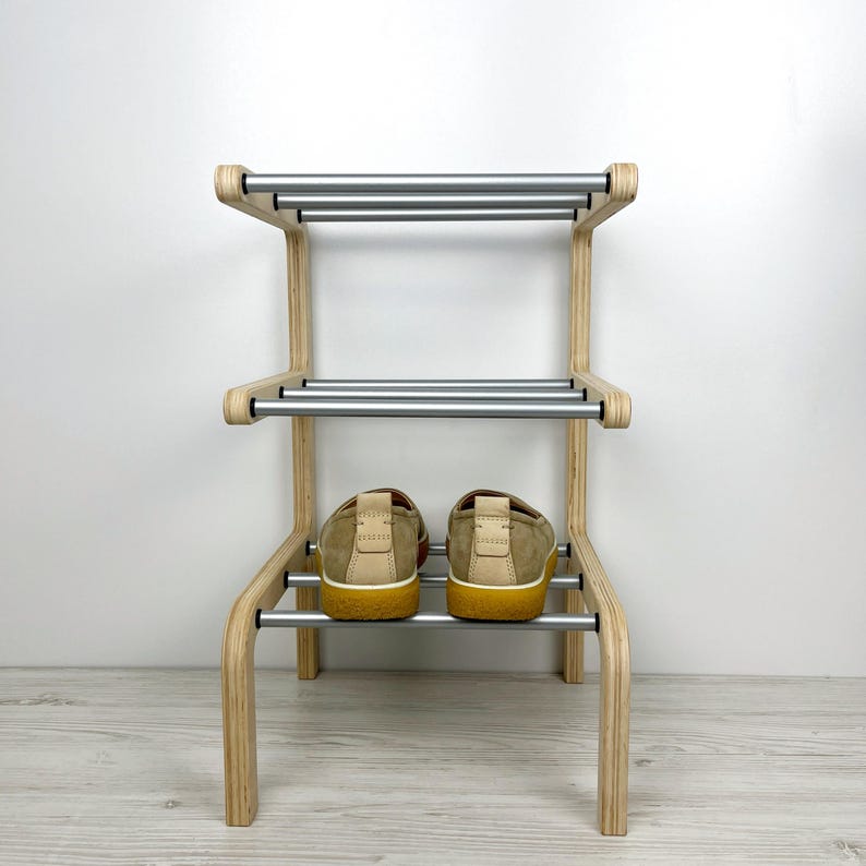 Pu&ograve; includere: Uno scarpiera in legno con due ripiani e binari in metallo argentato. Due paia di scarpe beige sono sullo scaffale inferiore.