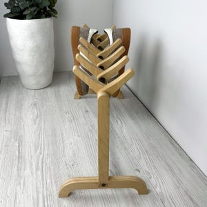 May include: A wooden shoe rack with a natural finish. The rack has six slots for shoes and a sturdy base. The rack is made of wood and is designed to hold shoes.