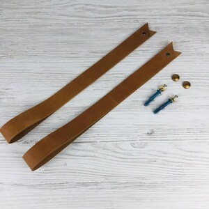 May include: Two brown leather straps with metal eyelets and two gold screws with blue plastic anchors.
