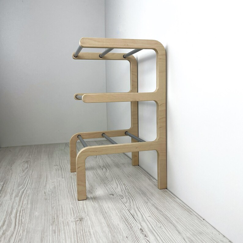 Pu&ograve; includere: Uno scarpiera in legno con tre ripiani e aste in metallo argentato. Lo scarpiera &egrave; realizzato in legno chiaro e ha un design moderno.