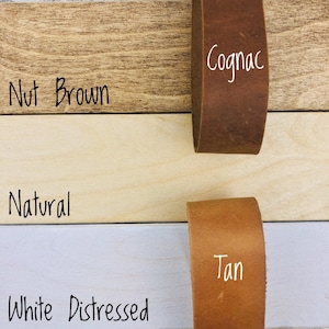 May include: Four leather straps in different colors: Nut Brown, Cognac, Natural, and Tan. The straps are displayed on a wooden surface.