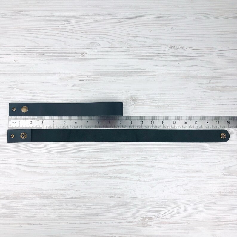Pu&ograve; includere: Due cinturini in pelle nera con rivetti in ottone, misurati con un righello. Il cinturino superiore misura 25,4 cm di lunghezza e il cinturino inferiore misura 48,3 cm di lunghezza.