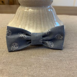 May include: A light blue bow tie with a white ladybug and bee pattern.